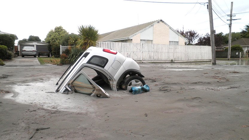 A car in a hole caused by liquefaction following the Christchurch earthquake