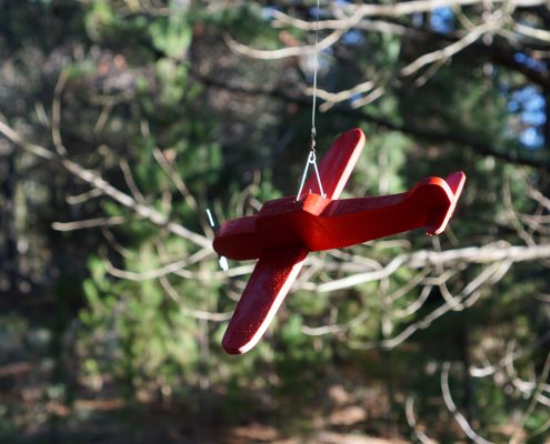 A red wooden toy plane hangs from the trees