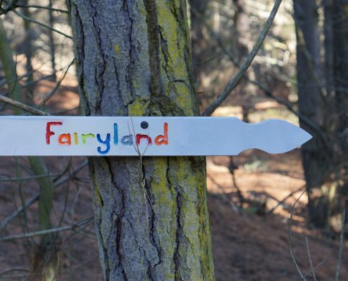 A white sign with colourful painted letters that say Fairyland