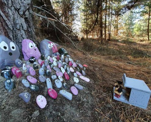 Purple and grey painted rocks sit in front of a small wooden concert stage