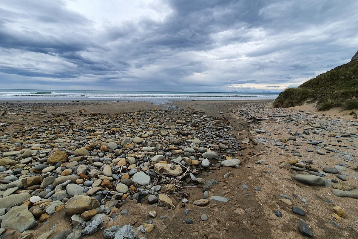 A stoney beach with grey clouds above